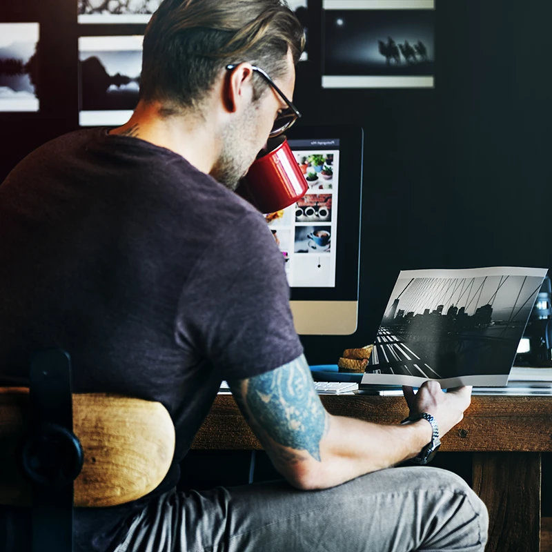 Freelancer revisando su trabajo en portátil, escritorio con pantalla y herramientas