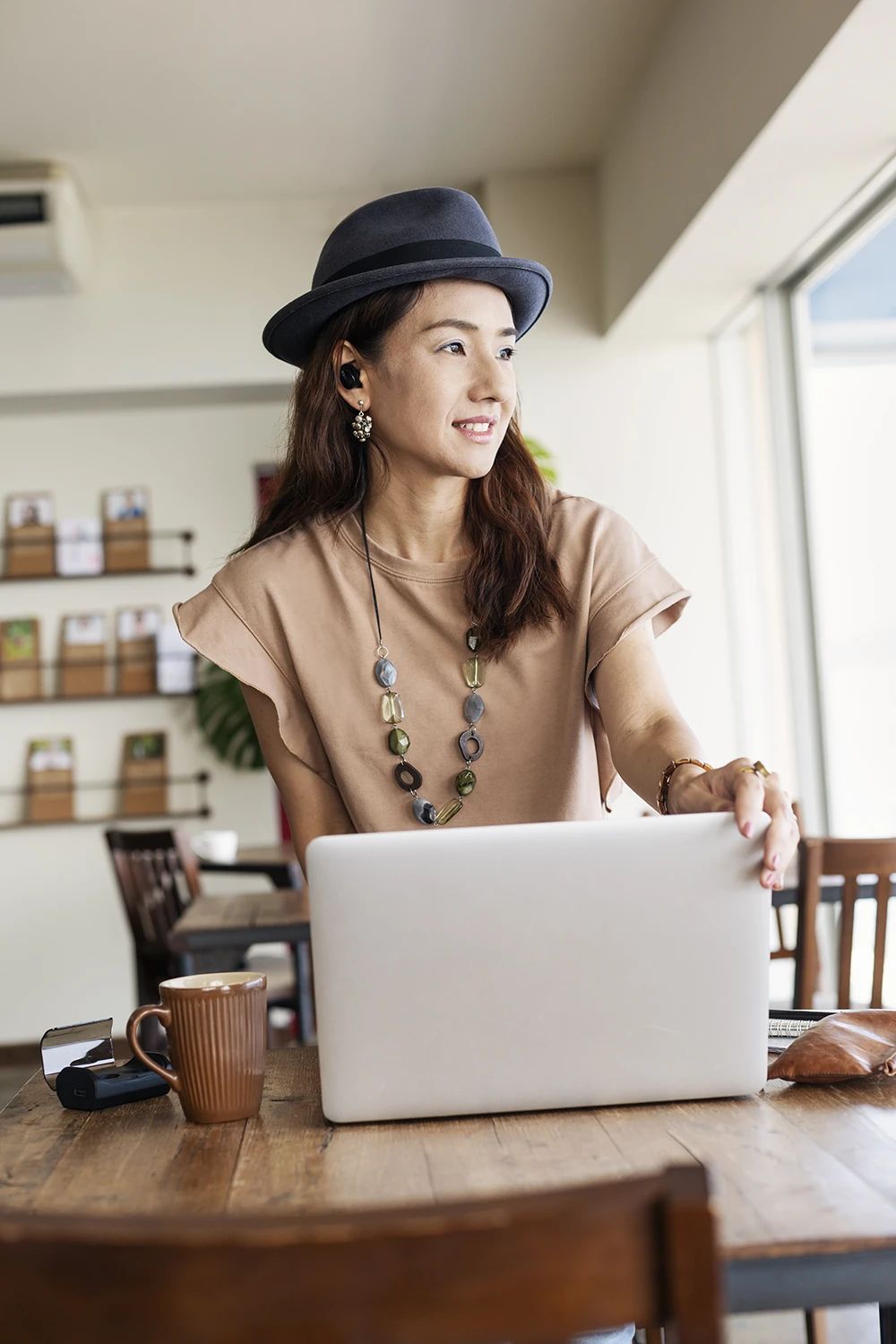 Mujer freelance organizando ideas y planificando trabajo en portátil desde una cafetería